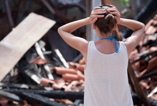 woman looking at destroyed house